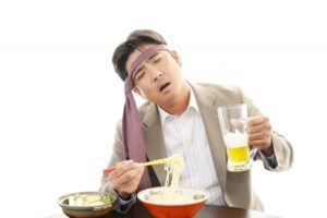 暴飲暴食のイメージ写真。頭にネクタイを巻く