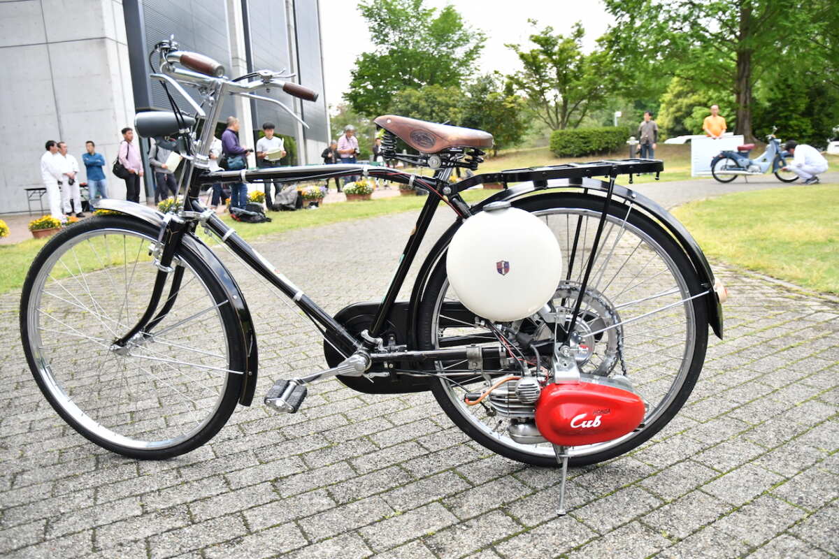 「白いタンク、赤いエンジン」の愛称で親しまれたホンダ カブF型／1952年。自転車の後輪に取り付ける補助エンジンで、ホンダのオートバイ躍進の基盤を築いた。（撮影：青木タカオ）