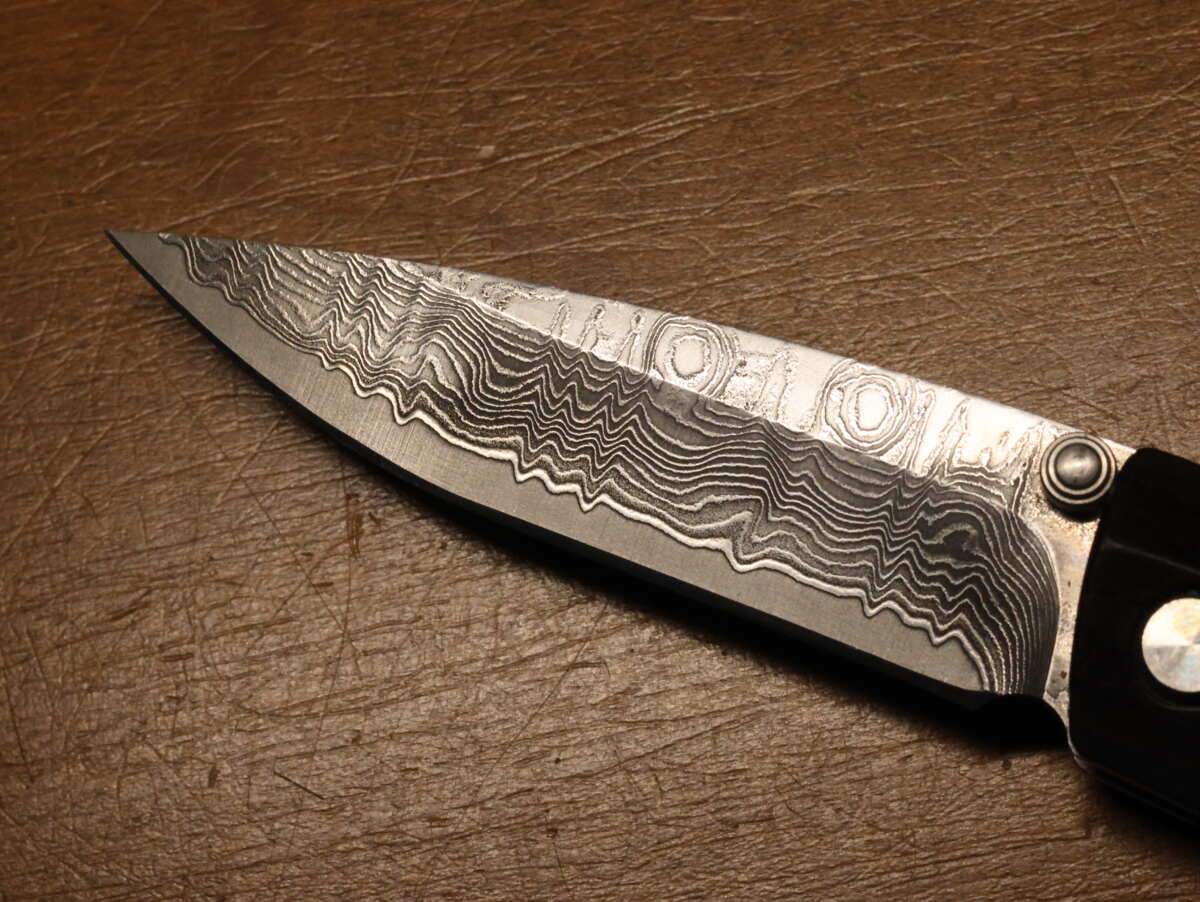 写真はアルミではなくダマスカス鋼という鋼（鉄）を使ったナイフだが、種類の違う鋼材を重ね、叩いて何度も折り重ねて伸ばしているために独特の模様が出る。