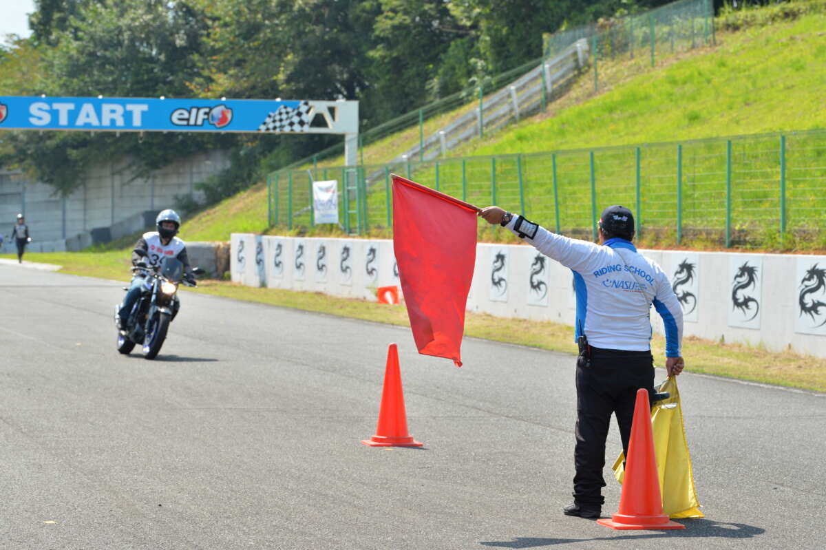 パイロンでの８の字、スラローム練習のあとは目標に向けてバイクを停止させるブレーキ技術の練度をアップ。講習では“旗とは逆の方向 へ進んで止まる”といったことも行い応用力も鍛える。