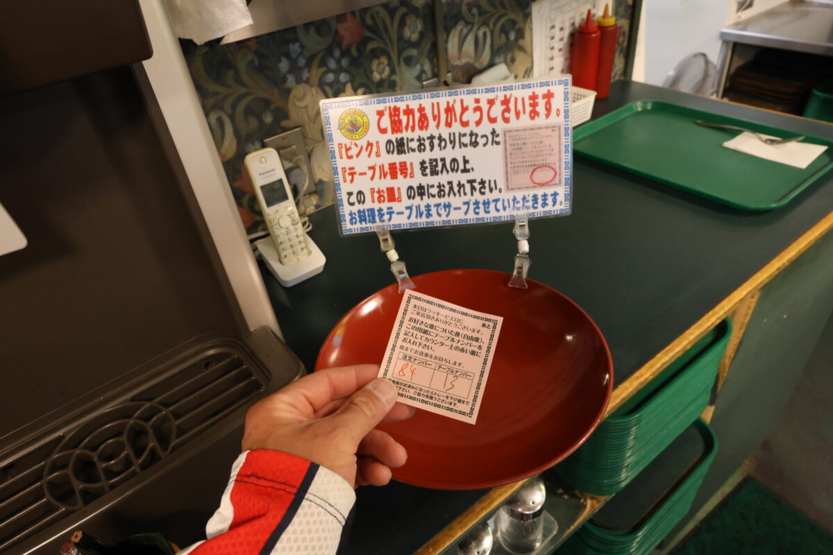 特徴的だったのが配膳システム。オーダーを行なって席に着いたら注文票にテーブル番号を書いたら、赤い皿の中に置く。するとスタッフが出来上がり後にテーブルまで品物を持ってきてくれるのだ。