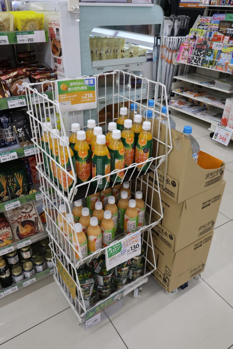 ん? 見たことないオレンジジュースだな……と思っているとセイコーマートのプライベートブランド商品だったのだ。しかも「国産果汁100%丸絞りみかんソーダ」は復活したらしい。ちなみに隣のダンボールの「京極の名水(ミネラルウォーター)」もセコマオリジナル。