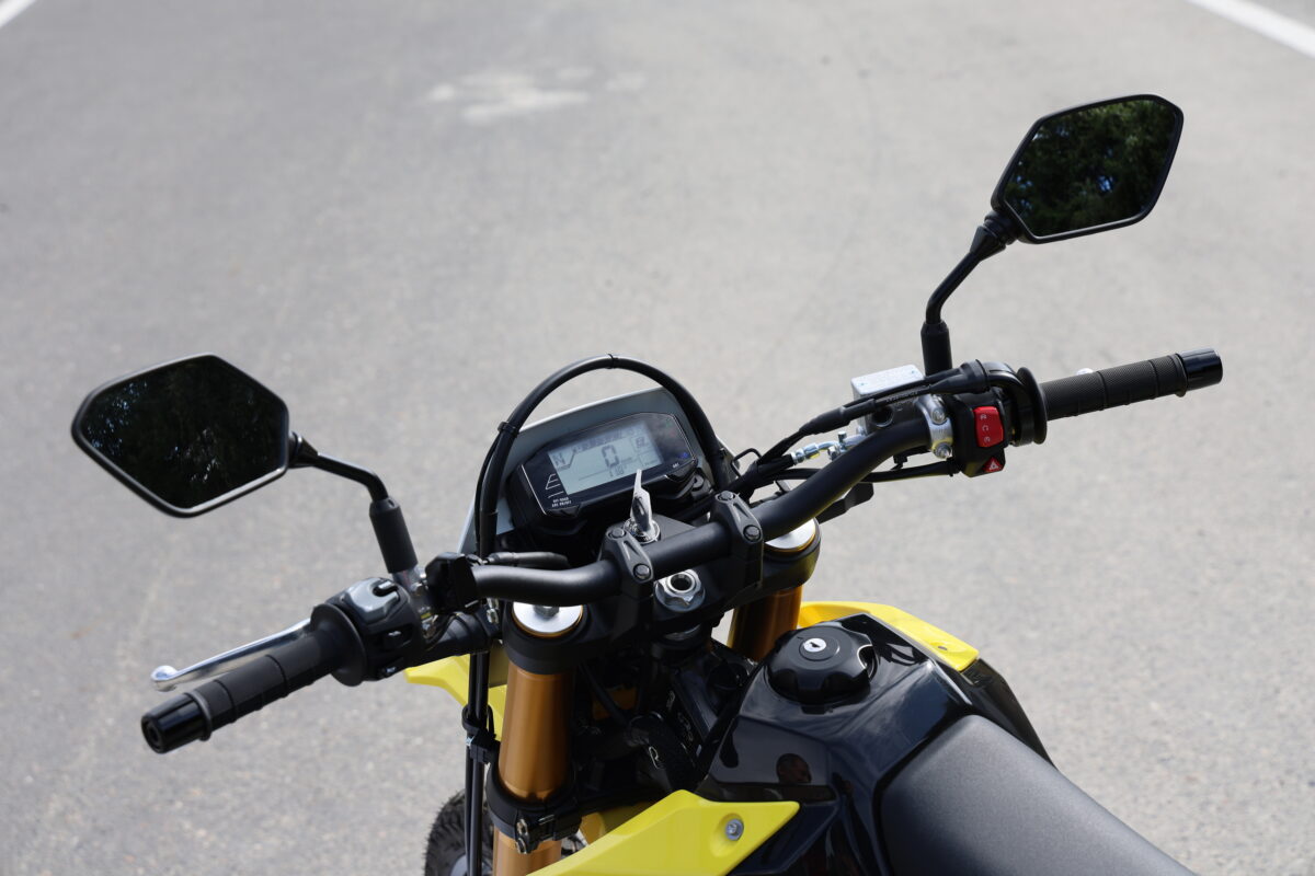 先代のスチール製ハンドルからアルミ製テーパーハンドルを採用。グリップポイントは先代のDR-Z400S比で28mmアップの2mmバック。ステップポジションも7mmアップして23mmバックしている。
