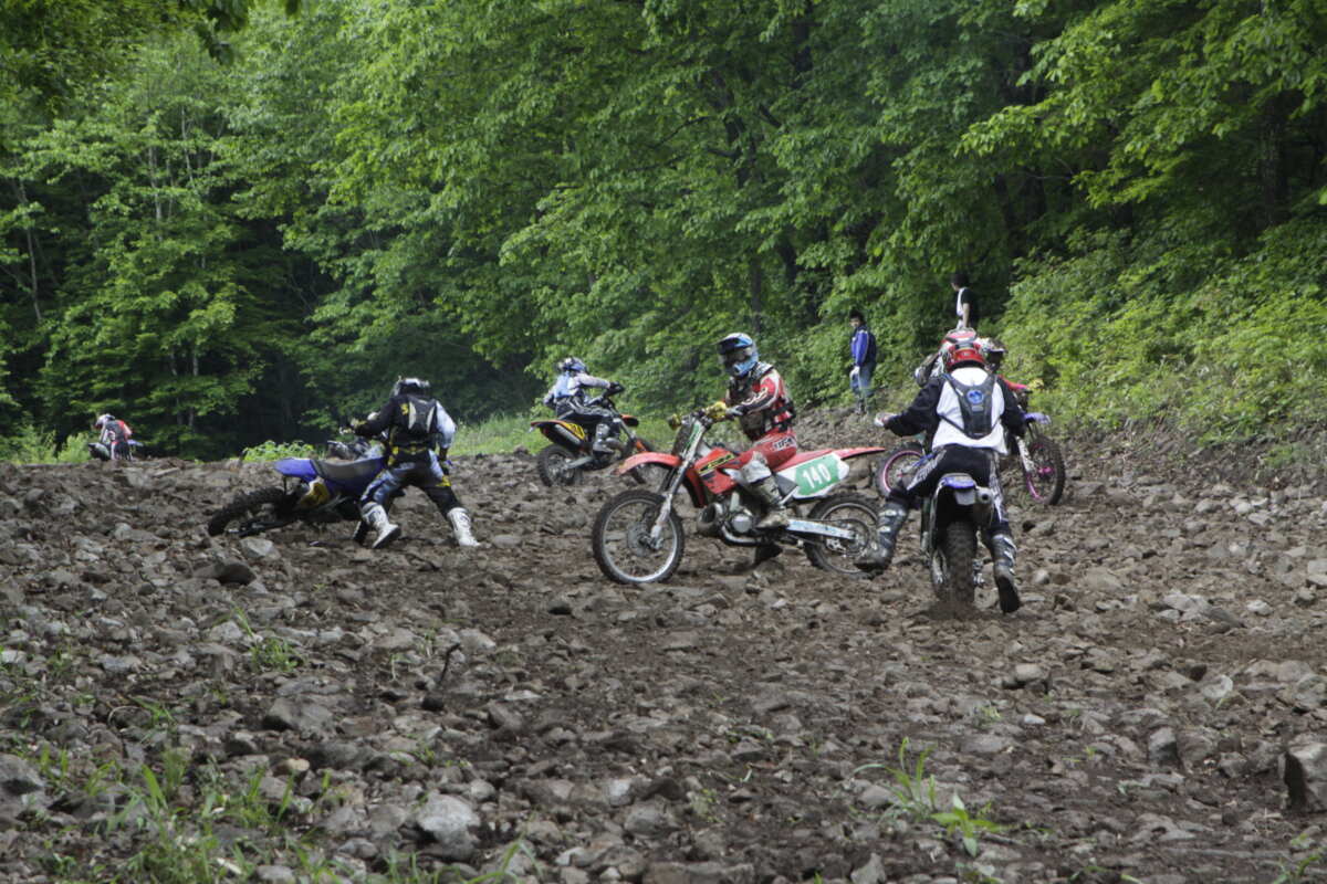 そうは見えないかもしれないがこれもエンデューロレースのワンシーン。エンデューロレースでは倒れたバイクを起こしたり、再チャレンジのために逆走したり、他のライダーと共闘してバイクを押し上げたり……。まぁ、地形や天候に翻弄されて舗装路の上を走るロードレースでは考えられないような阿鼻叫喚な状況になる。押したり引いたり、転んだりで心が折れるのだが、それがなんだか楽しい（笑）。