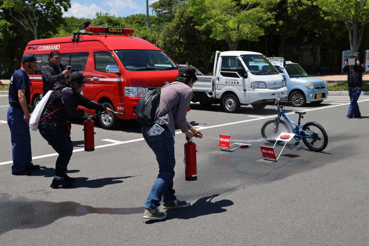 消化器を使った「初期消火講習消化器実用実演」では、来場者がバイクから発生した火災を想定した消火活動を体験。多くの来場者が参加していた。