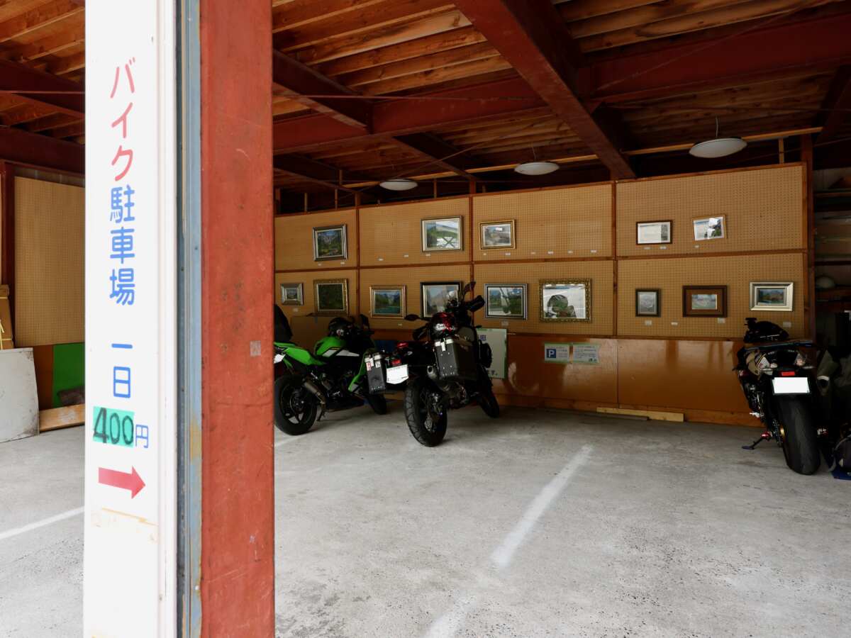 沢渡駐車場にある“温泉山小屋ともしび”のバイク駐輪スペース。スタッフが常駐しており、ハンドルロックをしない状態でバイクを預ける。駐車場代も1日400円と良心的で３泊予定の山行なら3日分を前もって支払う。
