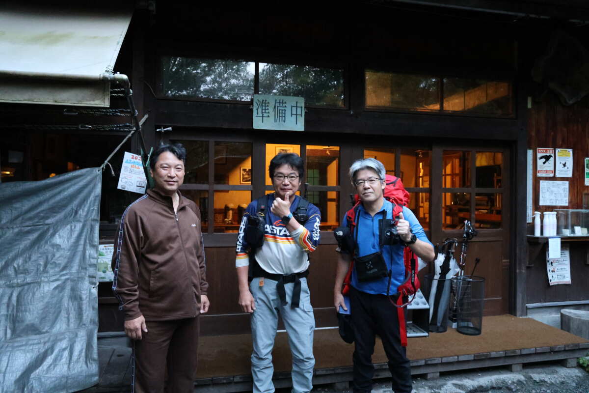 本日の宿は嘉門次小屋。上高地から梓川上流方面に1時間ほど歩いたところにある明神池ほとりの山小屋だ。ここで学生時代、槍ヶ岳山荘でアルバイトしていた時にいた従業員が働いており、“昔のバイト仲間で30ウン年ぶりに集まろう！”となったのが今回の山行の始まり（中央が筆者）。
